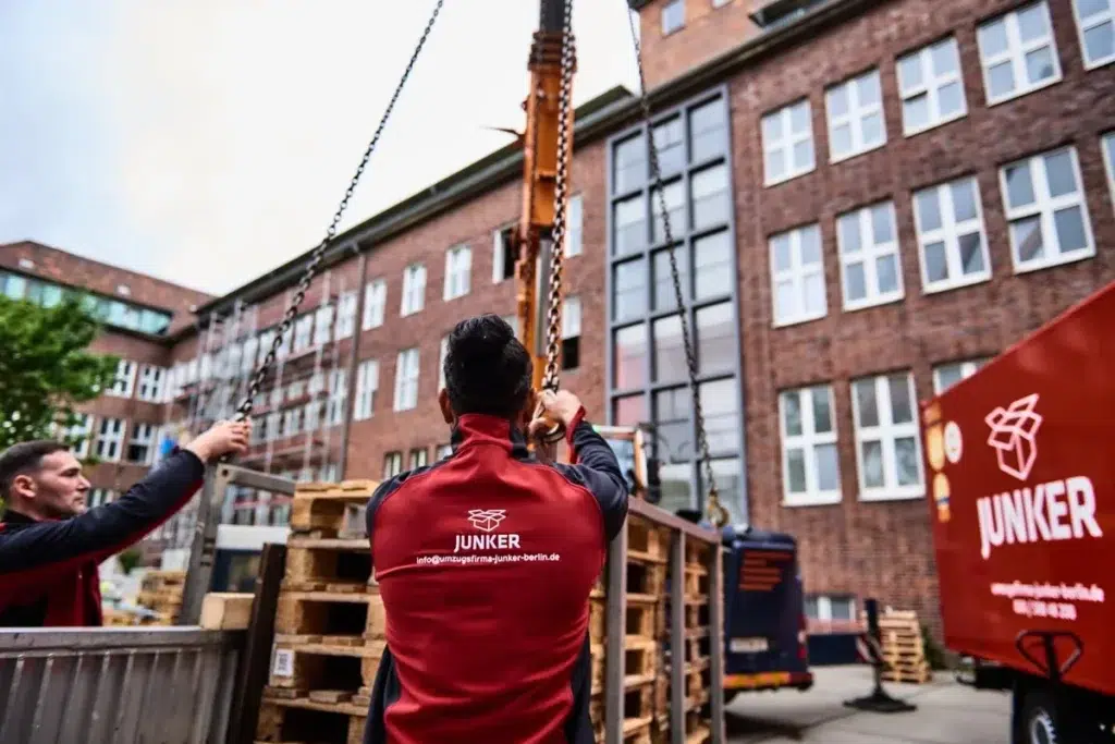 Junker Umzugshelfer steuern Kran für sicheren Möbeltransport in Berlin