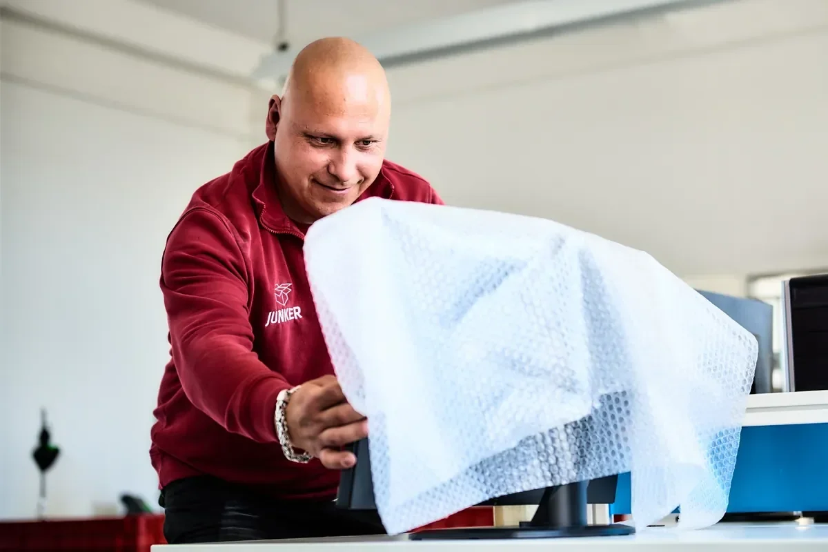Mitarbeiter der Umzugsfirma Junker verpackt einen Monitor für den Büroumzug