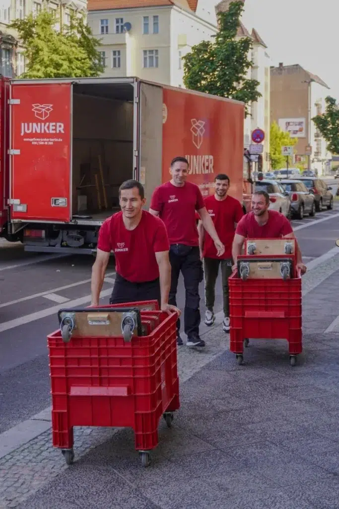 Junker Umzugsteam transportiert rote Rollwagen auf Berliner Straße