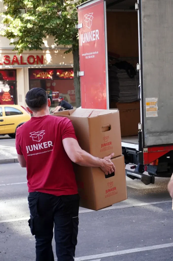 Umzugshelfer der Junker Umzugsfirma GmbH trägt Umzugskartons in Berlin