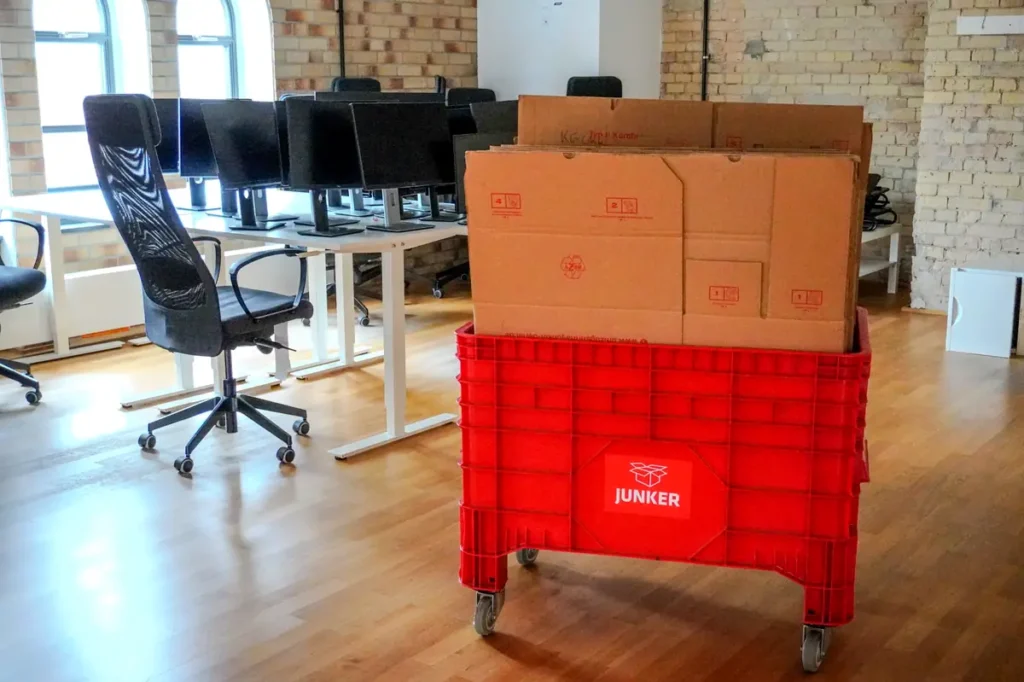 Roter Rollcontainer der Junker Umzugsfirma GmbH mit Umzugskartons in einem Berliner Büro