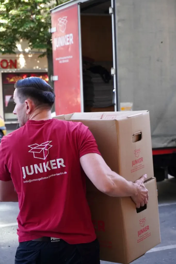 Umzugshelfer der Junker Umzugsfirma GmbH trägt Umzugskartons in Berlin