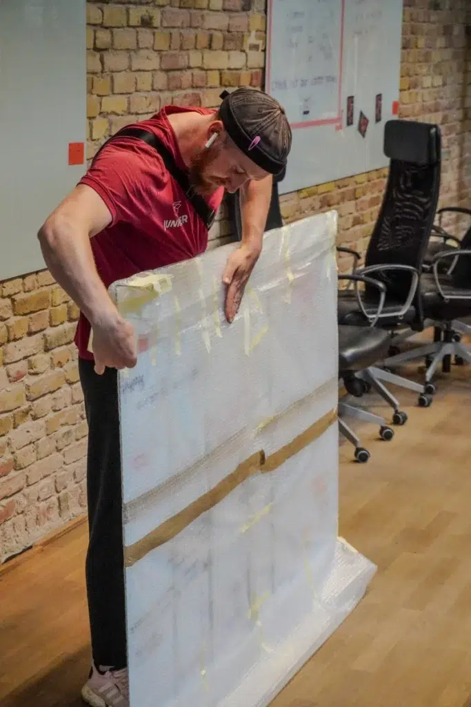 Mitarbeiter der Umzugsfirma Junker verpackt ein großes Kunstwerk mit Luftpolsterfolie