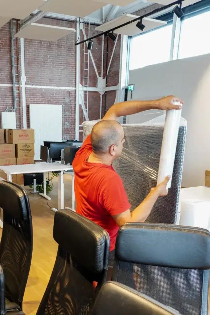 Mitarbeiter wickelt ein Möbelstück mit Luftpolsterfolie für den Umzug ein