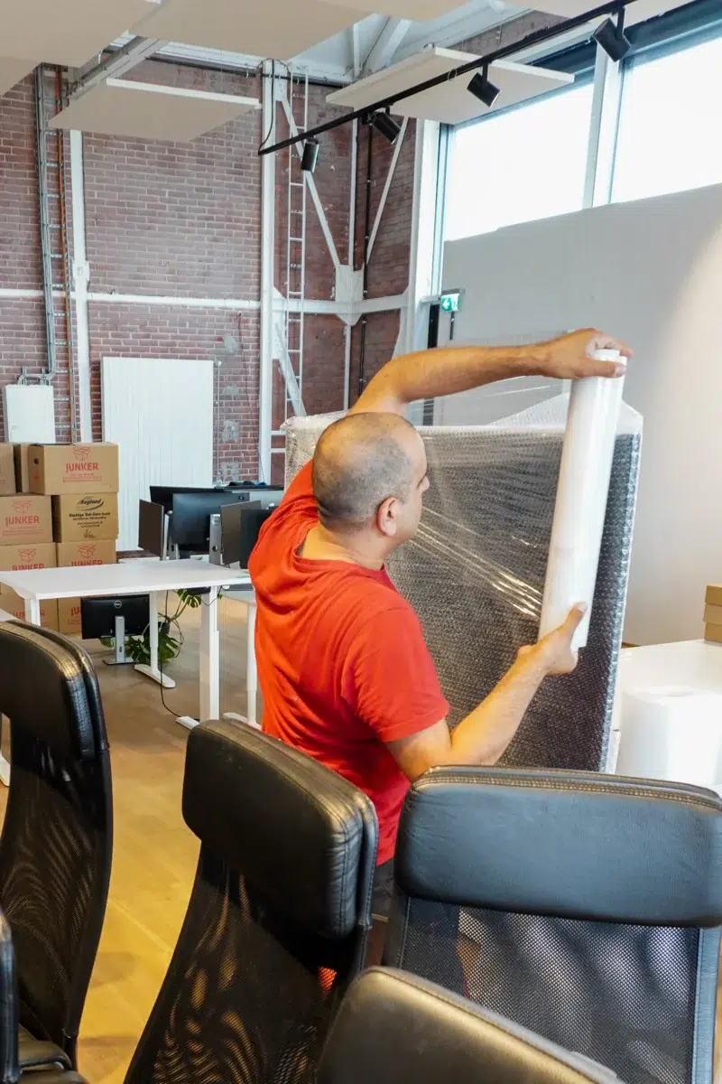 Mitarbeiter wickelt ein Möbelstück mit Luftpolsterfolie für den Umzug ein