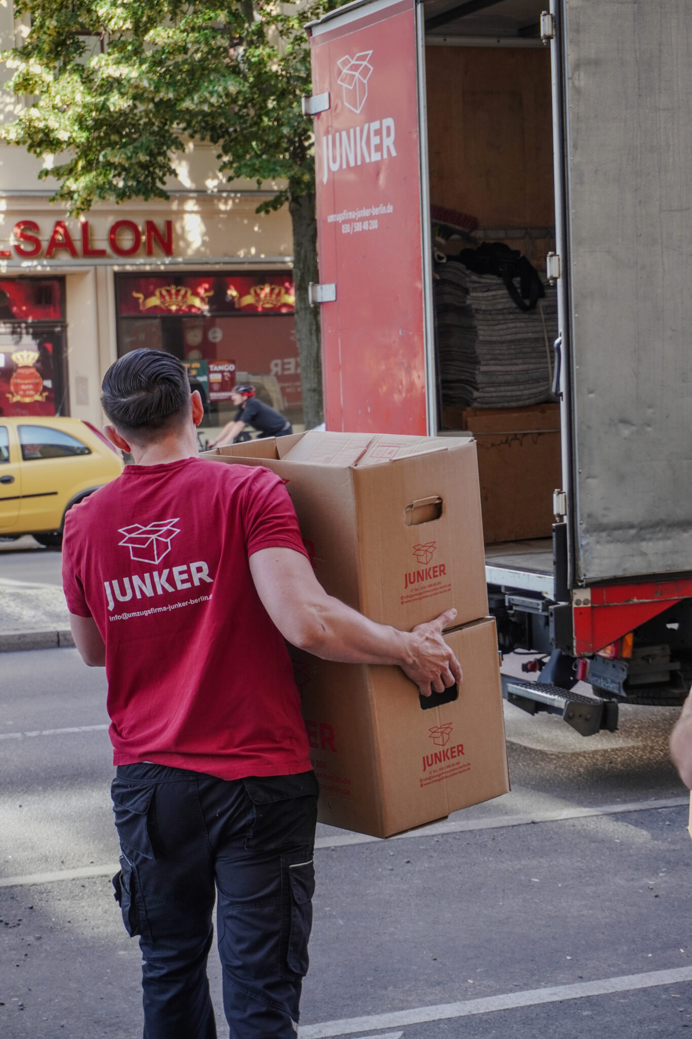 Umzugshelfer trägt Umzugskartons für eine Beiladung in Berlin – Junker Umzugsfirma GmbH.
